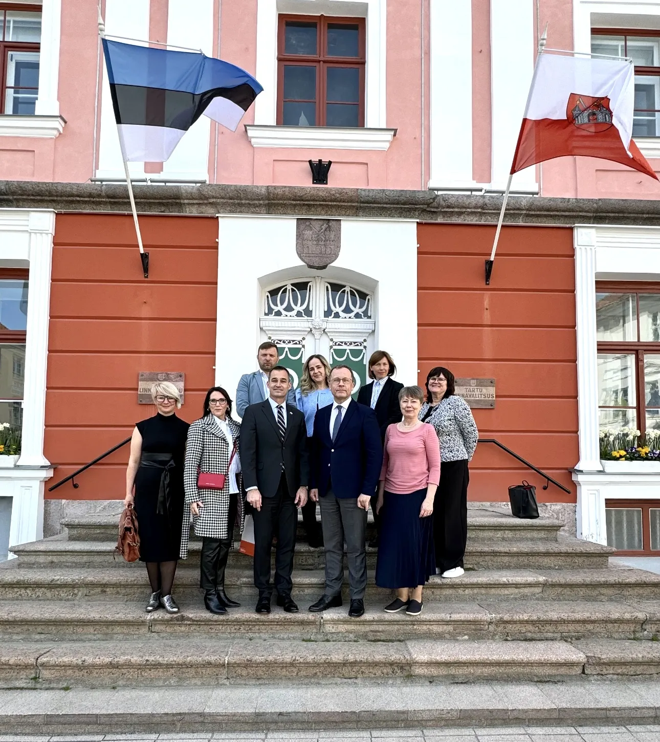 Fotol seisavad Tartu raekoja ees oleval Trepil Urmas Klaas, USA saatkonna tööd juhtiva ajutise asjur Matthew E. Wall ning saatjaskond.
