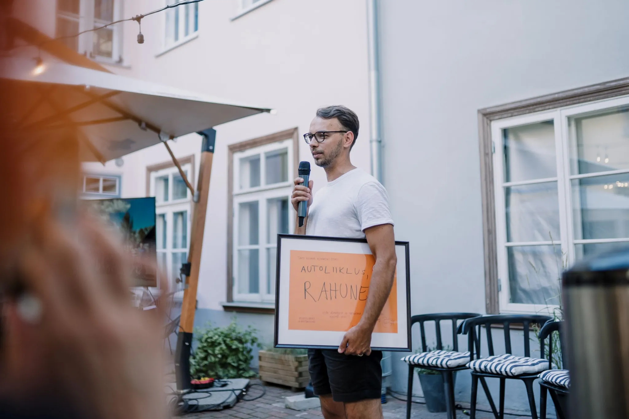 Tõnis Arjus räägib mikrofoni ja kaenlas on pilt tekstiga "Autoliiklus, rahune!"