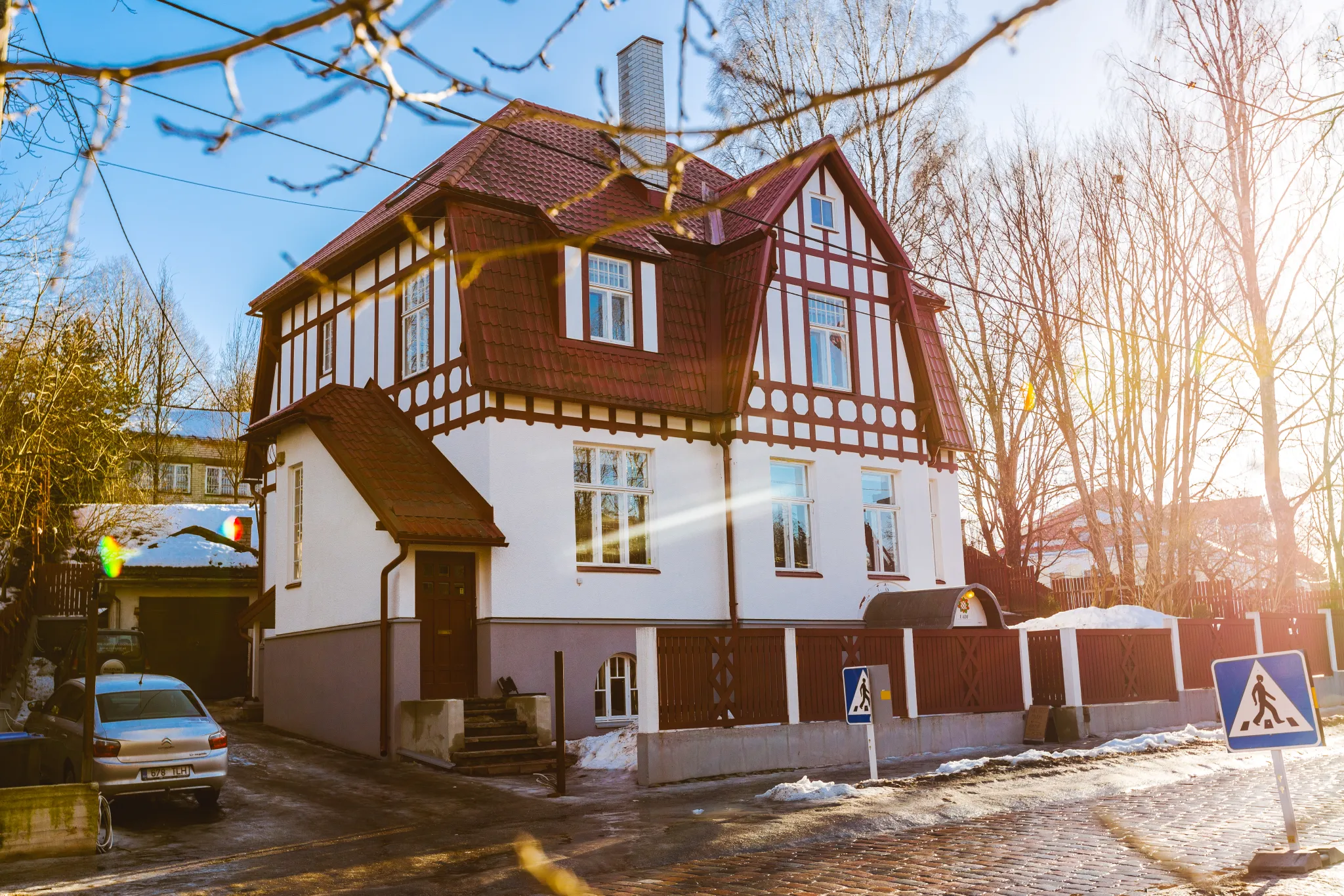 Lopsakas roheline aed, valge aiarkatus, värvikad taimed, väikene roosiline maja ning puidust aianõud.