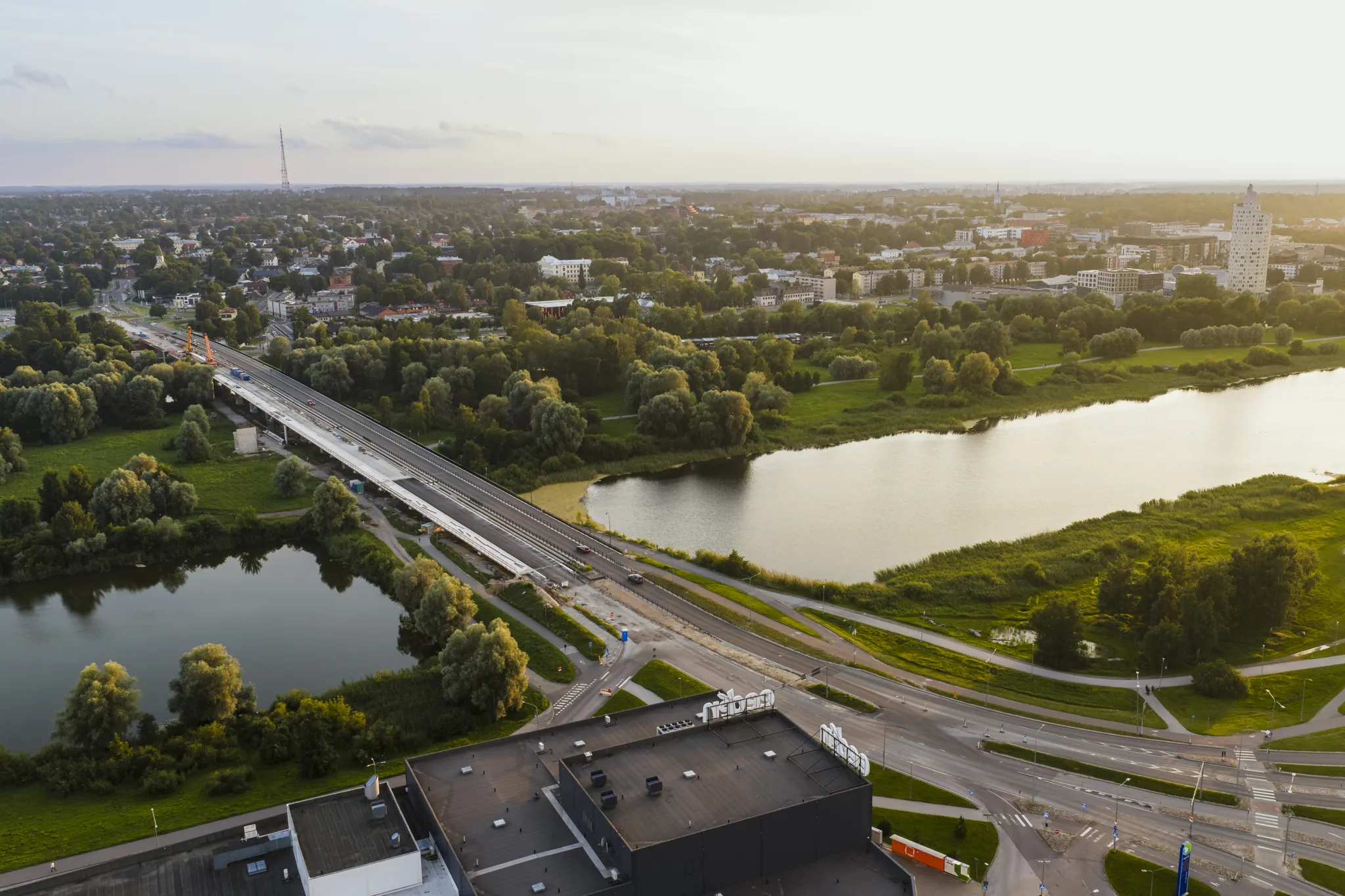  Lennuvaade Tartust, Eestist: jõgi lookleb roheliste parkide vahel, sild ulatub vee kohal, kaugusel on madalad hooned ja linna siluett.