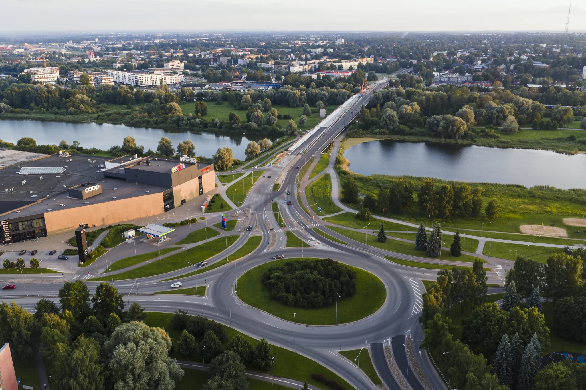  Õhupildil on suur ringristmik ja mitmel real ühendav maantee, mis ületab jõge. Teede ääred on rohelised; puud ja pargid. Taustal kaasaegsed hooned ja linna horisont.