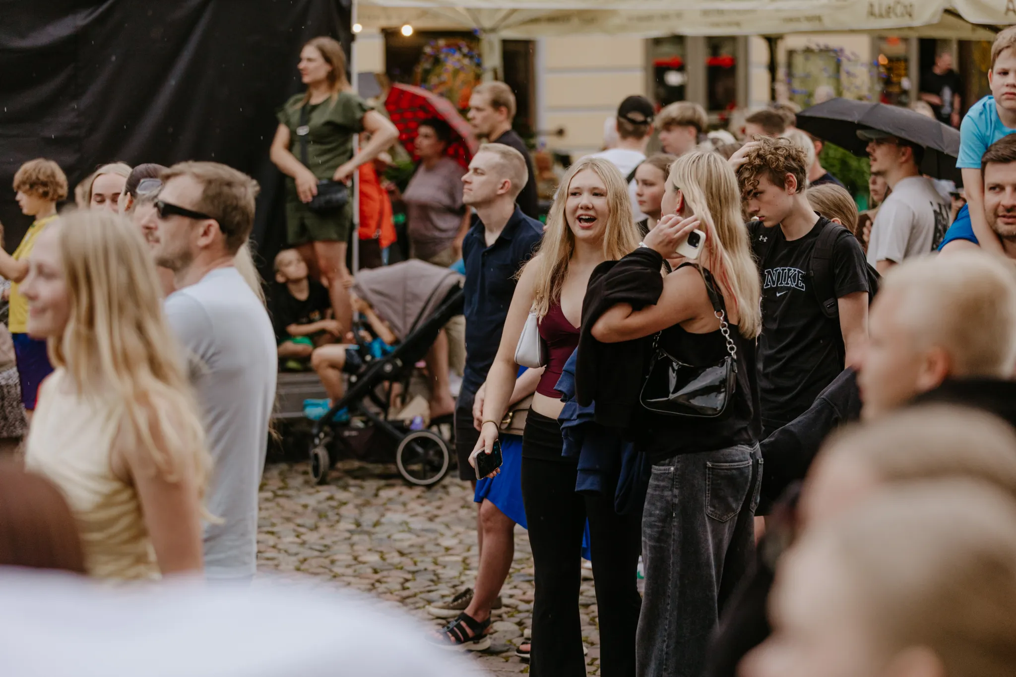  Elava välitekkiürituse rahvas Tartu vanalinna väljakul, inimesed vestlevad, naeravad ja jalutavad munakivist platsil.