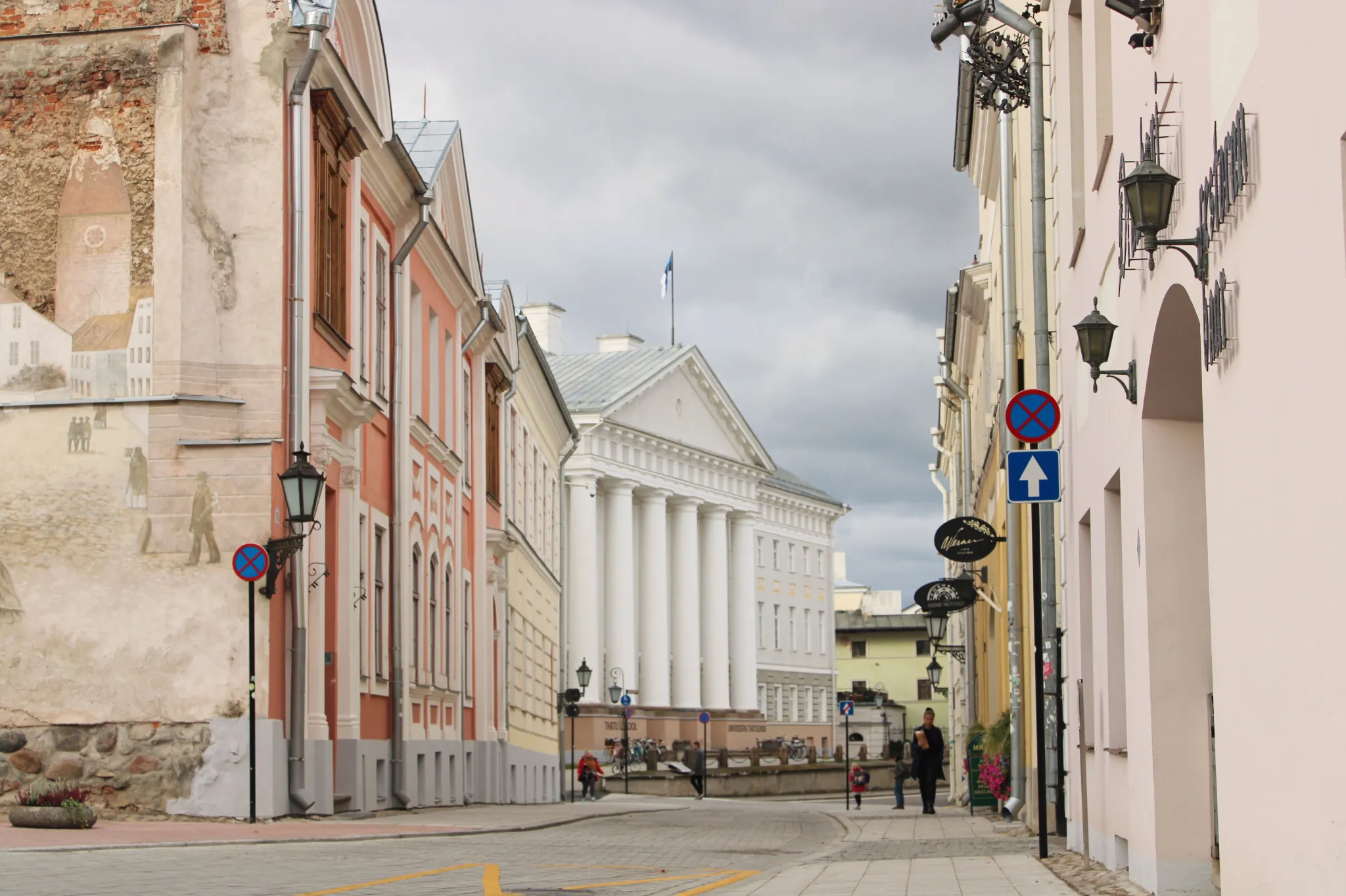 Tänavavaade Tartu kesklinnas. Keskel on näha Tartu Ülikooli peamaja valgete sammastega fassaad, mõlemal pool tänavat ajaloolised hooned.