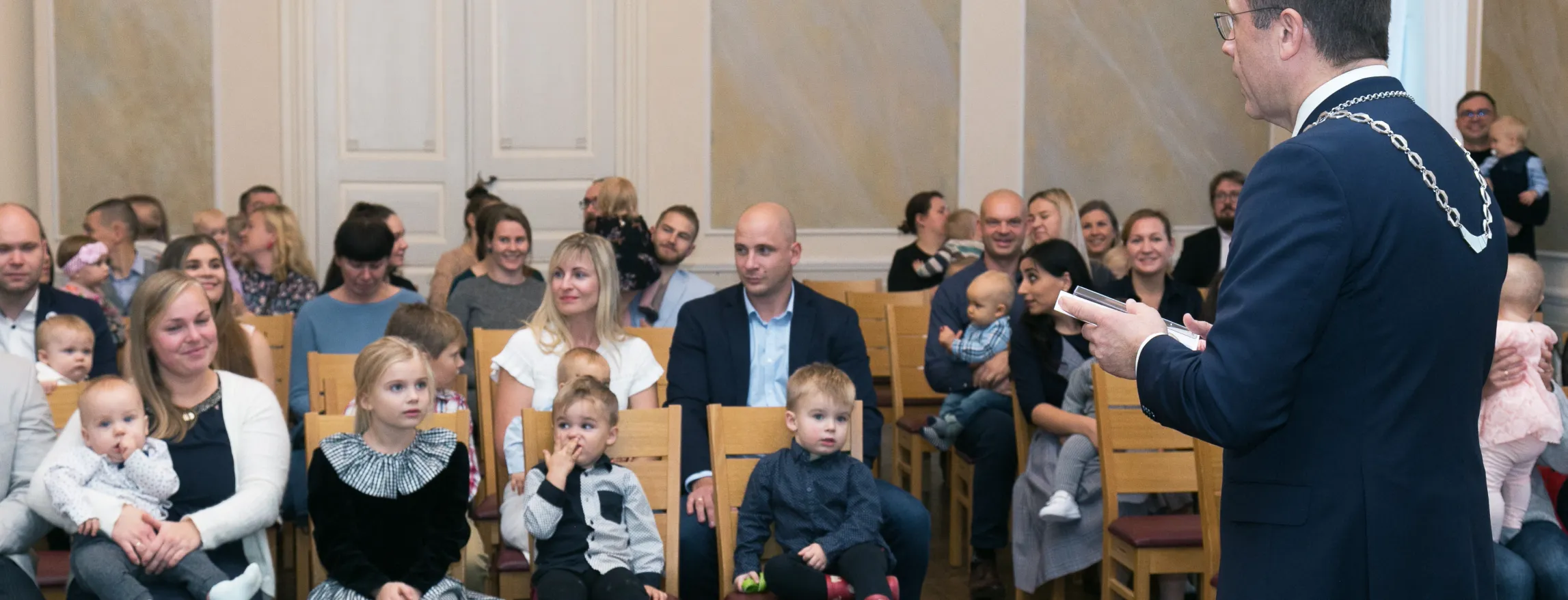 Linnapea Urmas Klaas seisab saali ees ja saalis istuvad vanemad koos lastega.