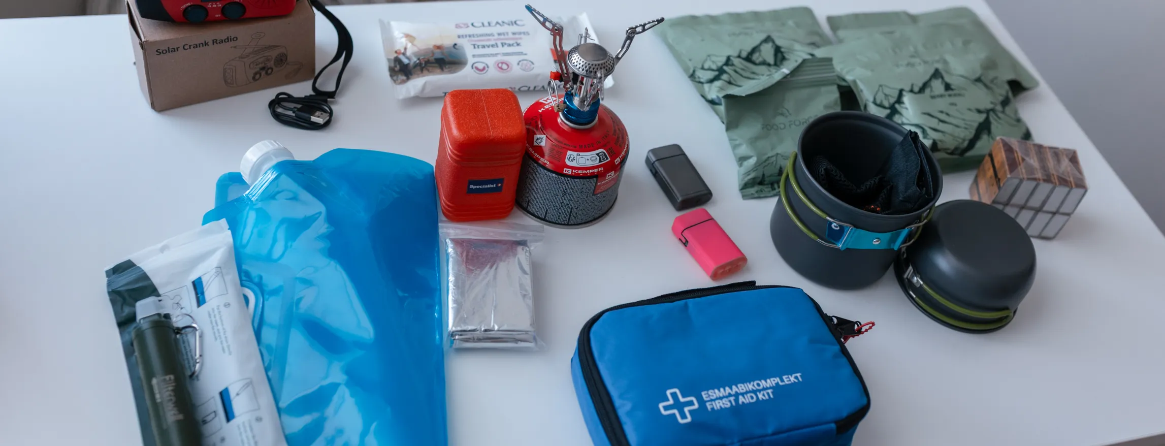  Laual reisieellujäämiskomplekt: sinine esmaabikott, sinine veekindel kott, kompaktne telkimispliit gaasiballoniga, roosa süütaja, hall laadija, kaardid, pealamp.