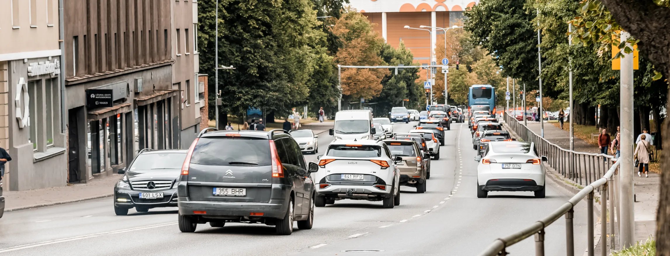 Pildil on Riia tänav, kus on näha sõitmas palju autosid. Otse tänava kõrval asuvad kortermajad. 