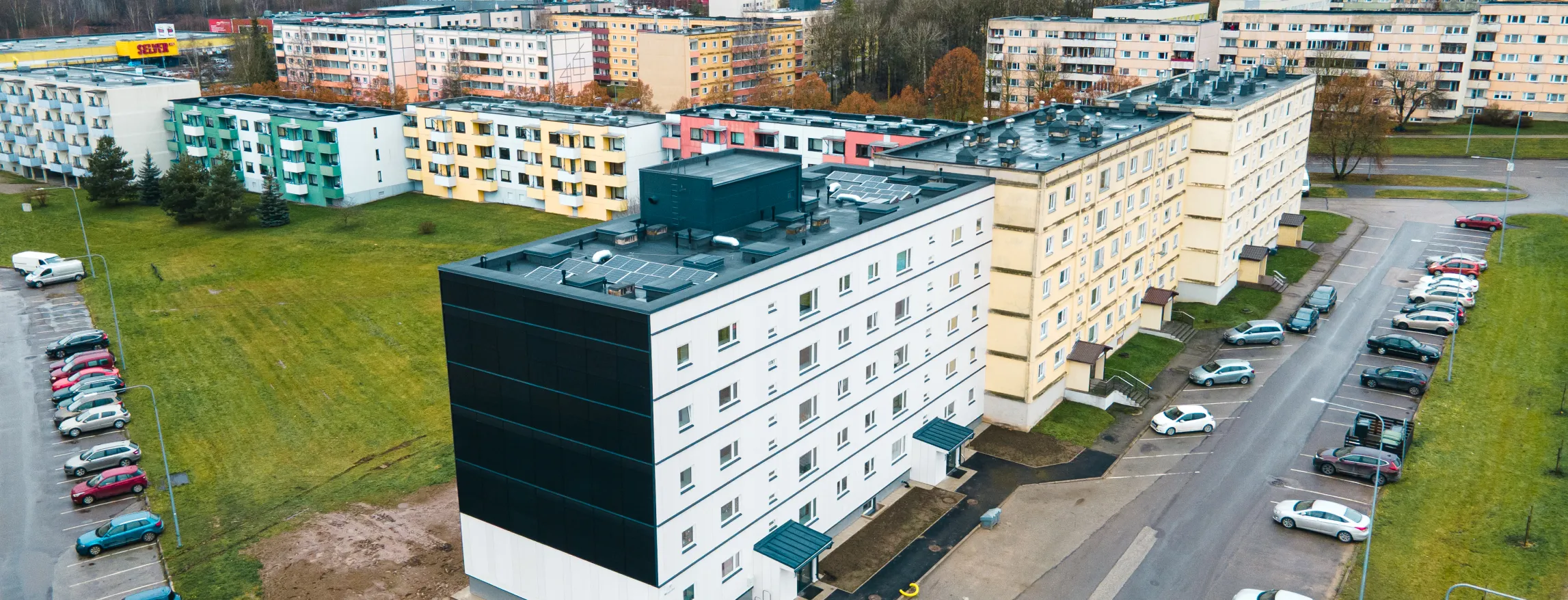 Droonifoto renoveeritud kortermajast. Katusel ja otsaseinal asuvad päikesepaneelid.
