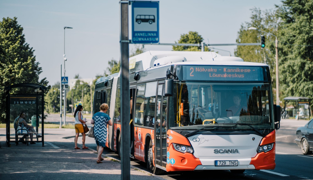 Buss peatuses, väljas soe suveilm, bussile lähevad suvistes riietes reisijad