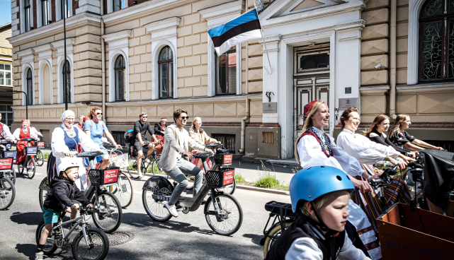 Laulu- ja tantsupeolised rongkäigus ja taustal maja peal lipp heisatud