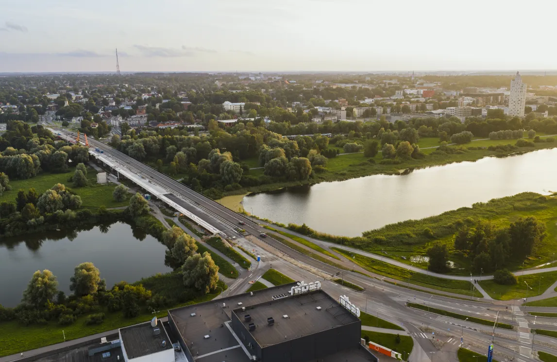  Lennuvaade Tartust, Eestist: jõgi lookleb roheliste parkide vahel, sild ulatub vee kohal, kaugusel on madalad hooned ja linna siluett.